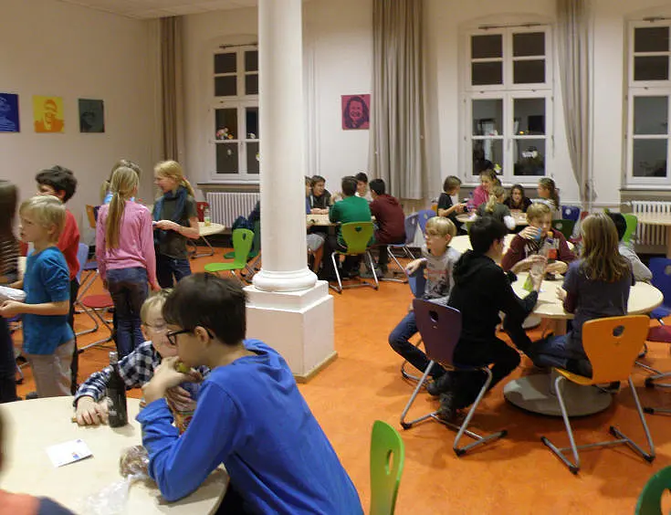 Sch&uuml;ler und Sch&uuml;lerinnen knobeln an Tischgruppen zu Mathematikaufgaben